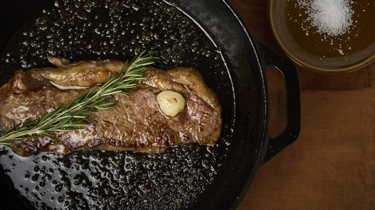 Steak cooking in a cast-iron skillet with rosemary and garlic