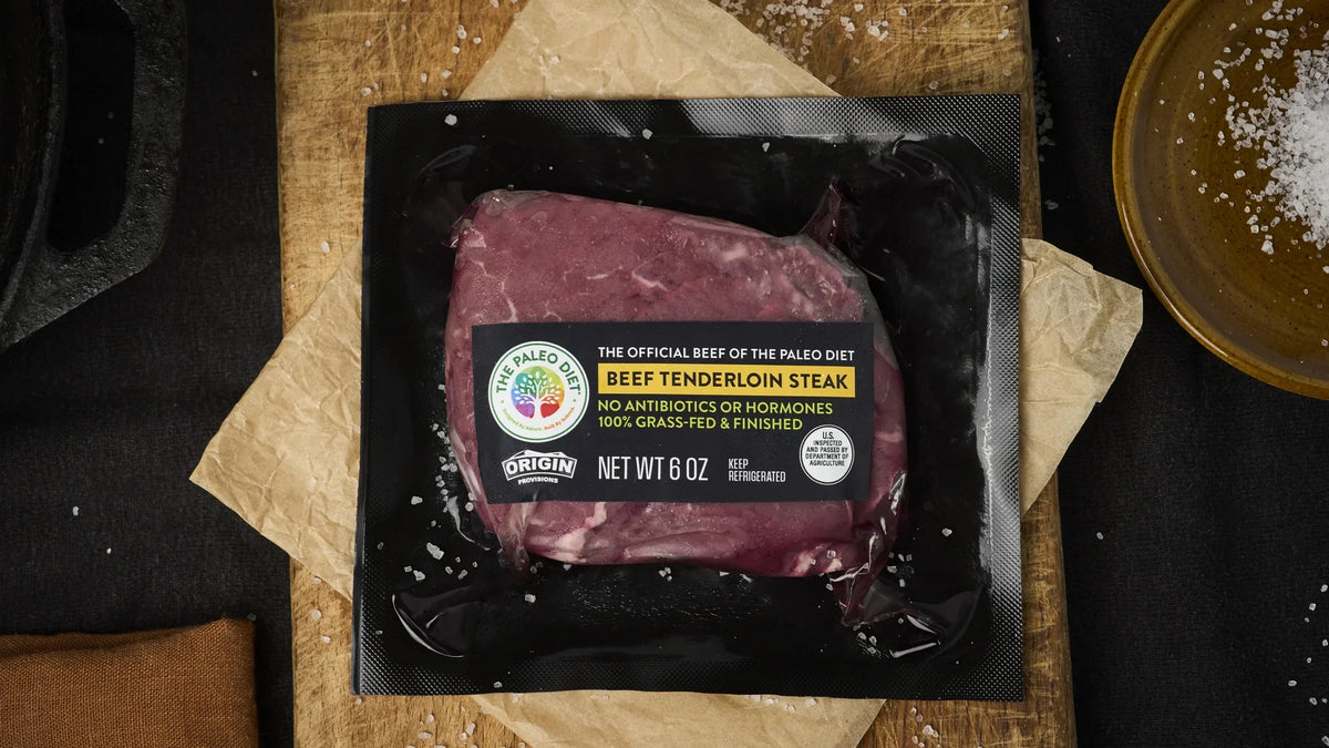 Origin Provisions tenderloin steak beside a cast-iron skillet with rosemary and garlic